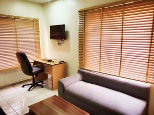 a living room with a couch and a desk with a computer at Central District Apartment (Abuja) in Aso