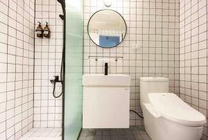 ein weiß gefliestes Bad mit einem WC und einem Spiegel in der Unterkunft 之跡 台北 in Taipeh