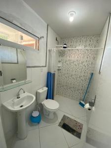 La salle de bains blanche est pourvue d'un lavabo et de toilettes. dans l'établissement Pousada Raio de Sol - Ilha de Itaparica- Catu á 150 m da praia, à Vera Cruz de Itaparica