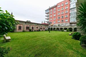 a green yard with benches in front of a building at Cómodo y moderno piso en Vigo by CABANA Rentals in Vigo