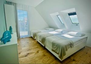 a white bedroom with two beds and windows at Apartamenty Spacerowa 27 in Niechorze