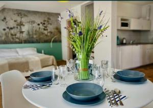 a white table with blue plates and a vase of flowers at Apartamenty Spacerowa 27 in Niechorze