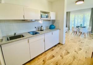 a kitchen with white cabinets and a wooden floor at Apartamenty Spacerowa 27 in Niechorze