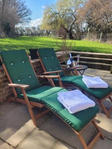 two green lawn chairs sitting on a patio at Honeysuckle Cottage with hot tub near Needham Market in Ipswich