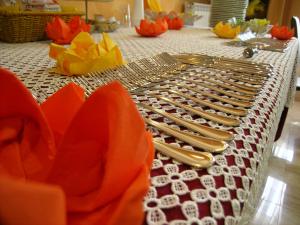 una mesa con cubiertos de plata y flores naranjas. en Hotel Air Palace Lingotto, en Turín