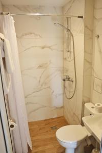 La salle de bains blanche est pourvue d'une douche et de toilettes. dans l'établissement Rilena Hotel, à Kiten