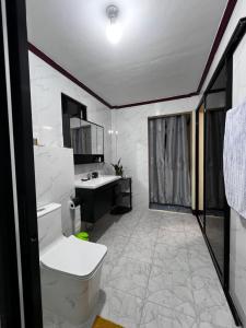 a bathroom with a white toilet and a sink at Joymendz in San Jose de Buenavista
