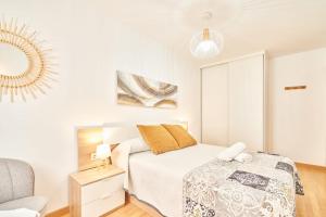 a white bedroom with a bed and a chair at El retiro de nirvana in Castellanos de Moriscos