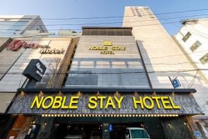 Una señal de hotel de nelle stay frente a un edificio en Jamsil Noblestay Hotel, en Seúl