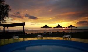puesta de sol sobre una piscina con sillas y sombrillas en Casuta camping BenBeach 
