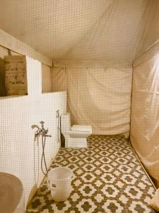 La salle de bains est pourvue de toilettes et de carrelage. dans l'établissement Jaisalmer Royal Desert Safari Camp, à Sām