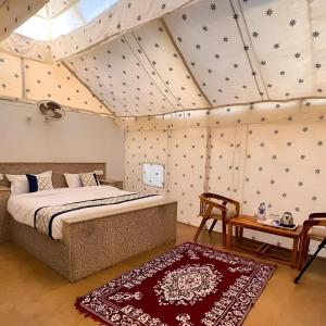 - une chambre avec un lit et une table dans l'établissement Jaisalmer Royal Desert Safari Camp, à Sām