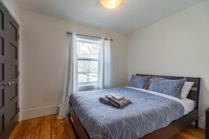 a bedroom with a bed with a blue comforter and a window at Beautiful & Spacious Apt #101 in Halifax