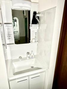 uma casa de banho com um lavatório branco e um espelho. em Shinjuku Waseda House Station 2mins em Tóquio