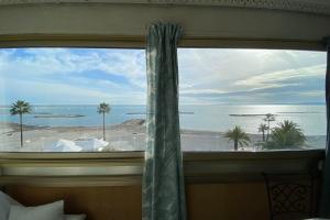 a bedroom window with a view of the ocean at 06BH - Beautiful seafront studio in Saint-Laurent-du-Var