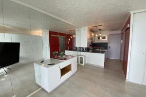 a kitchen with white cabinets and a flat screen tv at 06BH - Beautiful seafront studio in Saint-Laurent-du-Var