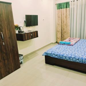 1 dormitorio con 1 cama y TV. en Nester Rooms, en Guwahati