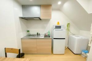 una pequeña cocina con nevera y microondas en Guest House HARU DREAM ABENO HOUSE, en Osaka