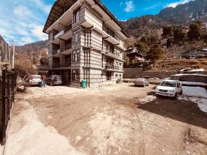 Mountain View Resort - A Hidden Resort Manali في مانالي: مبنى كبير فيه سيارات تقف امامه