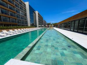 a swimming pool with chairs and a building at Resort com Piscina Aquecida e Garagem em Xangri-lá in Xangri-lá