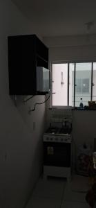 uma pequena cozinha com um fogão e uma janela em APARTAMENTO EM ILHÉUS - PRAIA DOS MILIONÁRIOS - VOG ATLÂNTICO - Pé na Areia em Ilhéus