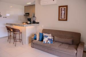 a living room with a couch and a kitchen at Imbassaí Apartments in Imbassai