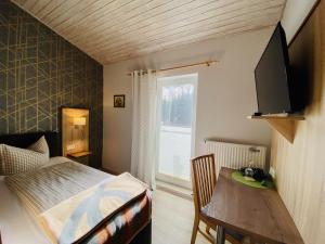 Schlafzimmer mit einem Bett, einem Tisch und einem Fenster in der Unterkunft Hotel Zur Kutsche in Oberschöna