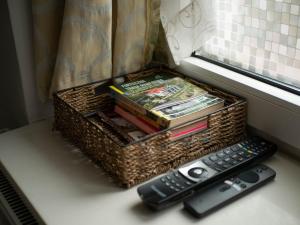 un panier avec des livres et une télécommande à côté d'une fenêtre dans l'établissement Apartament przy synagodze, à Przemyśl