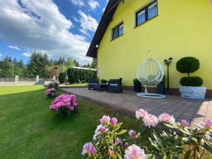 a yellow house with a patio and flowers at Apartamenty i pokoje w Zawoi Dorota Miśkowiec in Zawoja