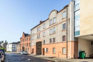 ein großes Backsteingebäude auf einer Straße mit geparkten Autos in der Unterkunft KM Hotel in Edinburgh