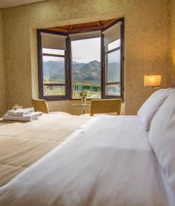 a bedroom with a large bed with a large window at Ayres de Uco Lodge & Wine Lovers in Los Árboles