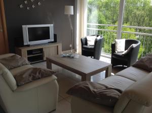 uma sala de estar com uma televisão e uma mesa e cadeiras em Moderne woning Malmedy em Malmedy