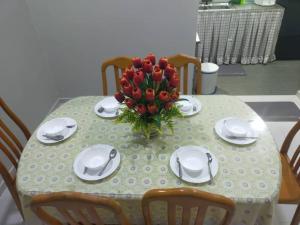een tafel met een vaas met rode bloemen erop bij A YIE HOMESTAY in Kuantan