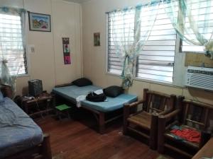 a room with a bed and a chair and windows at Bugoy Bikers Hostel in Cebu City