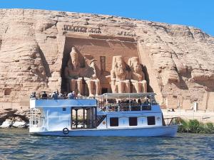 Un barco en el agua con una estatua. en Kony Nubian Guest House, en Abu Simbel