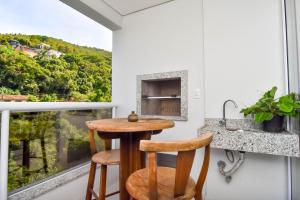 a kitchen with a table and two stools in front of a window at Apto 2 quartos, 350 mts Primavera Garden e ACM P2079 in Florianópolis