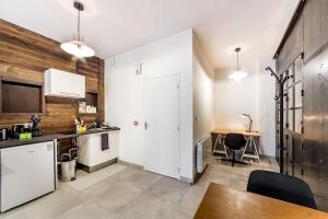 een keuken met witte kasten en een houten muur bij Superbe studio style industriel à Charbonnière in Charbonnières-les-Bains