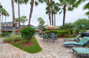 a patio with chairs and tables and palm trees at Resort Hotel Condo near Disney parks - Free parks shuttle in Orlando