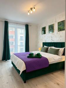 a bedroom with a large bed with a purple blanket at Luxury Glam Apartments Sibiu near Station and Mall in Sibiu