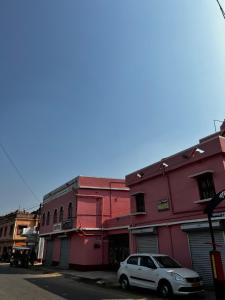 een witte auto geparkeerd voor een roze gebouw bij RATNA NIBAS 