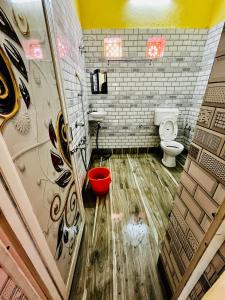 a bathroom with a toilet and a red bucket at RATNA NIBAS 
