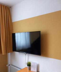 TV de pantalla plana colgada en la pared en Hotel Karolinger en Düsseldorf