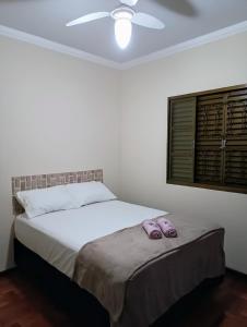 - une chambre avec un lit et 2 chaussons violets dans l'établissement Acomodação Confortável, à Sarandi