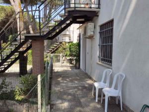- deux chaises blanches installées à côté d'un bâtiment avec des escaliers dans l'établissement Holiday Homes in Rosolina Mare 48310, à Rosolina Mare
