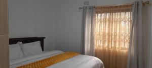 Schlafzimmer mit einem Bett und einem Fenster mit Vorhängen in der Unterkunft PGD Homes & Lodges in Blantyre
