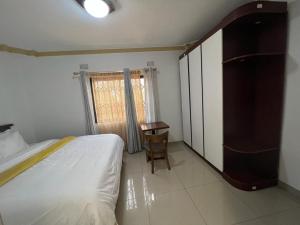 a bedroom with a bed and a table and a window at PGD Homes & Lodges in Blantyre