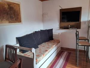 Habitación pequeña con cama, TV y silla. en Casa de Boneca, en Campos do Jordão