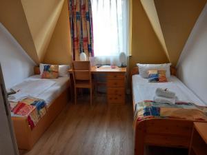 two beds in a room with a desk and a window at Hotel Karolinger in Düsseldorf