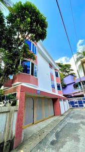 un edificio rojo y blanco con un árbol delante de él en Kumar Para Deluxe Villa en Sylhet