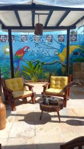 2 sillas y una mesa frente a un mural en Pousada Lua Vermelha, en Caponga
